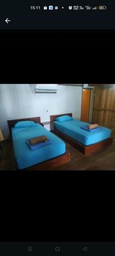 two beds with blue sheets in a room at Iboih inn in Sabang