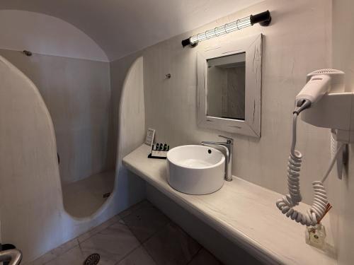 a white bathroom with a sink and a mirror at Diamond on the cliff Hotel&Suites Imerovigli in Imerovigli