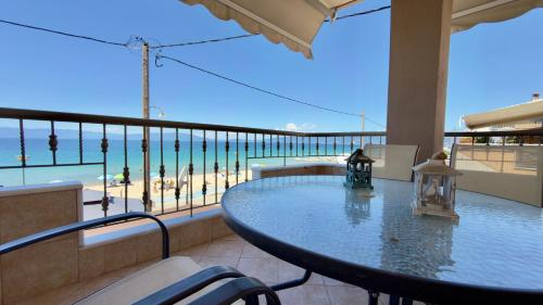 a balcony with a table and a view of the beach at Remvi Beachfront Suites by Horizon Homes in Orfánion