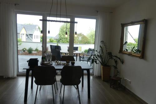 a dining room with a table and chairs and a large window at Ferienwohnung Wolkenfeld in Kaisersesch