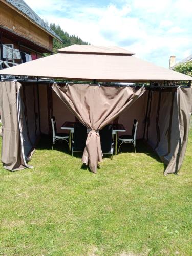 a tent with chairs under it on the grass at Sadyba u Vani in Volovets