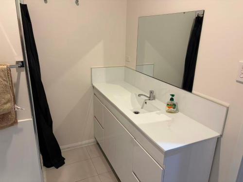a white bathroom with a sink and a mirror at The Bass Horizon - 5 bedrooms - 10 people - Bass Strait View in Devonport