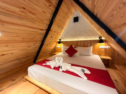 a bedroom with a bed with two towels on it at Pahadi Sukoon - A frame Cottages in Dharamshala