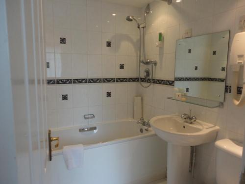 a bathroom with a sink and a bath tub and a sink at Dial House Hotel in Crowthorne