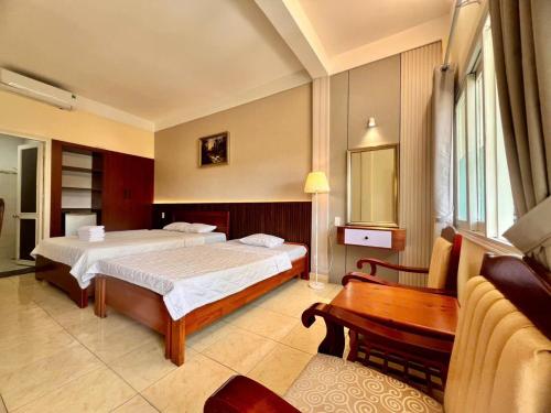 a hotel room with two beds and a desk at Lam Son Hotel in Vung Tau