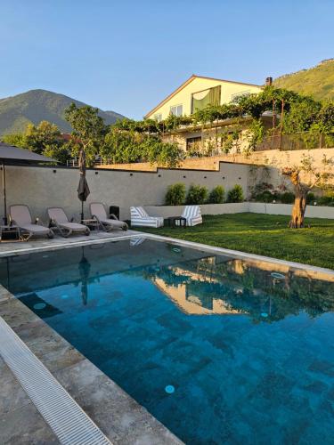 a swimming pool with chairs and a house at Vila 1985 in Tirana