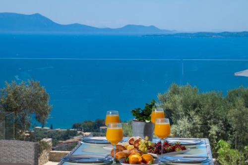 a table with a plate of food and orange juice at Eleage Villas in Lefkada