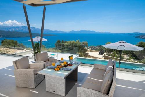 a patio with a table and chairs and a view of the water at Eleage Villas in Lefkada