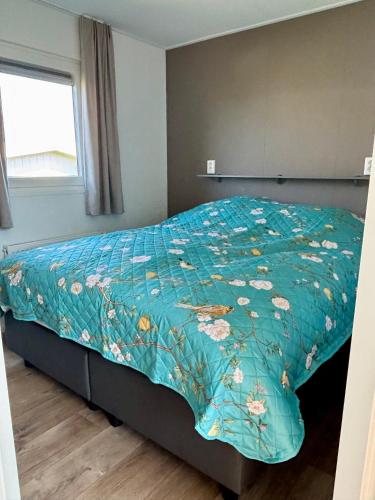 a bedroom with a bed with a blue comforter at Chalet Wad'n Droom in Westerland