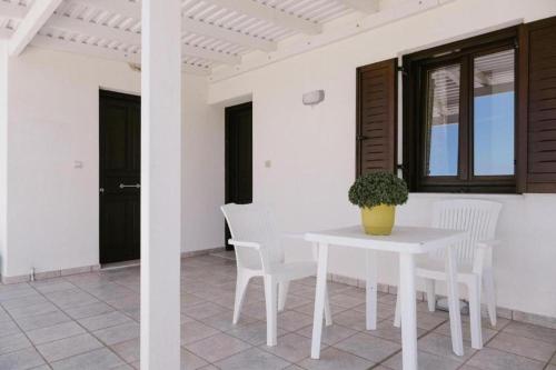 a white table with white chairs and a vase on it at Iliaxtida apartments II in Grámousa