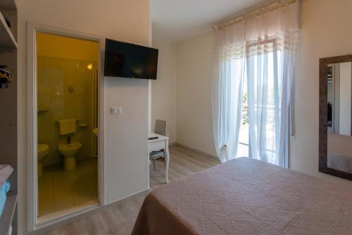 a bedroom with a bed and a bathroom with a toilet at B&B Santiago in Milano Marittima