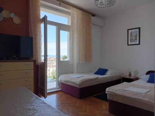 a bedroom with two beds and a television and a window at Villa BORIĆ DARKO in Podgora