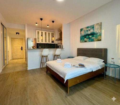 a bedroom with a large bed and a kitchen at MAYA Studio-Onix Blue with Private Parking, Mamaia Nord in Mamaia Sat/Năvodari