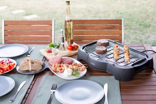 a grill on a table with plates of food at Špulka Hideaway - Romantic Forest Escape near Prague in Teplýšovice