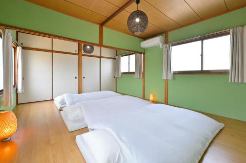 a bedroom with a white bed and green walls at Shion 潮音 in Sakaide