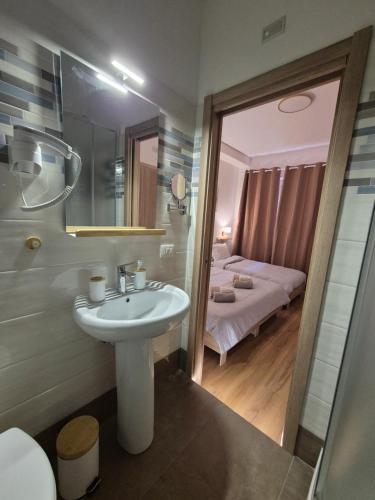 ein Badezimmer mit Waschbecken und ein Zimmer mit Bett in der Unterkunft Civico181 in Cisterna di Latina
