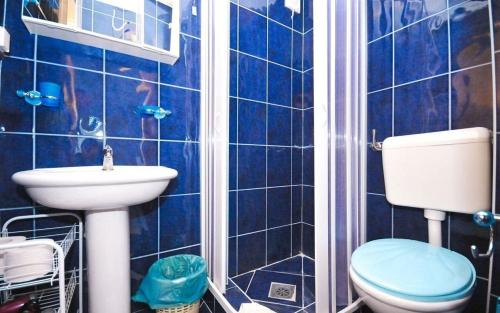 a blue tiled bathroom with a toilet and a sink at Stojko Rafailovici in Rafailovici