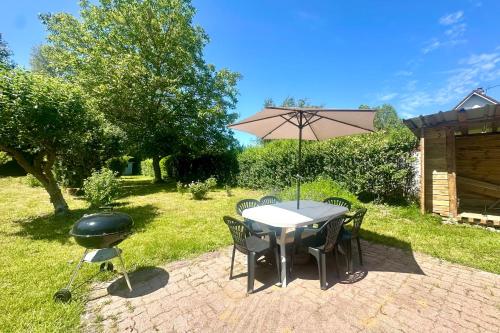 a table and chairs with an umbrella and a grill at Maison avec jardin entre St-Valery et Le Crotoy in Noyelles-sur-Mer