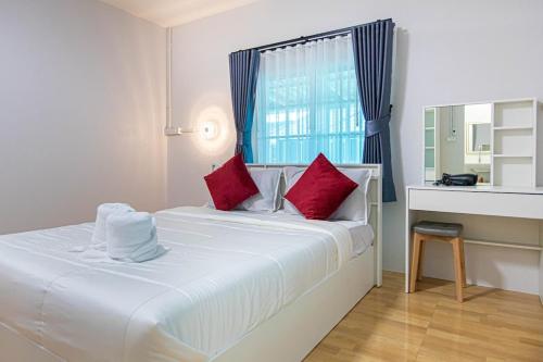 a white bed with red pillows in a room at The Comfy House Prachuap in Sathani Rot Fai