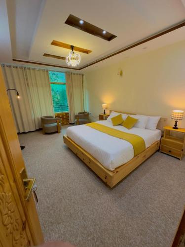 a bedroom with a large bed and a large window at Gems Palace Hotel Naltar in Jugut