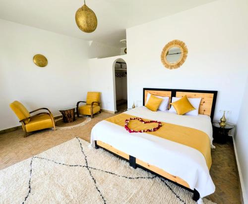 a bedroom with a king sized bed and yellow chairs at Dar Diyafa Marrakech in Maout
