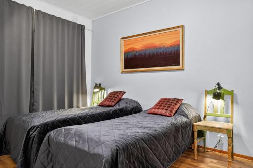 a bedroom with two beds and a chair at Cozy two-room apartment with sauna in Sodankylä