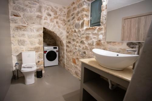 a bathroom with a white sink and a stone wall at Mainotti's house in Areopoli