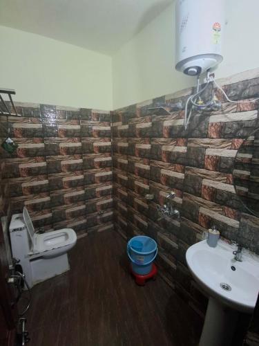 a bathroom with a toilet and a sink with a brick wall at Hotel AAA And Restaurant in Gupta Kāshi