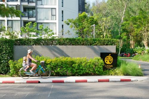 a woman riding a bike with a child on it at Cassia Phuket, part of Banyan Group in Bang Tao Beach