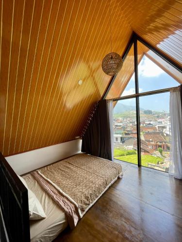 a bed in a room with a large window at Kaffana Cabin House in Banjarnegara