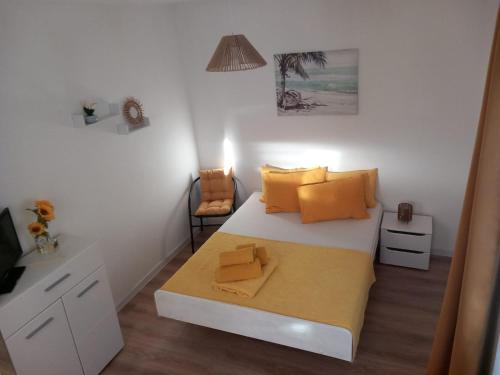 a bedroom with a bed with yellow pillows and a chair at ApartmaniNET in Krašići