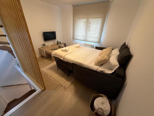 a bedroom with a bed and a desk and a television at Casa Caracol in Cambados