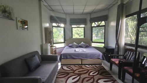 a bedroom with a bed and a couch and windows at Lamphun Garden Home in Lamphun