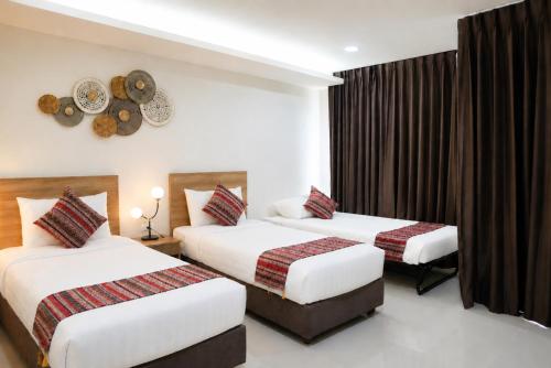a hotel room with two beds and a clock on the wall at Christella Hotel Laemchabang in Si Racha