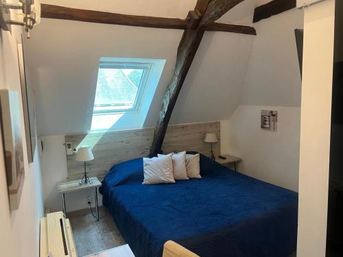 a bedroom with a blue bed and a window at Le Jaonnet in Nabirat