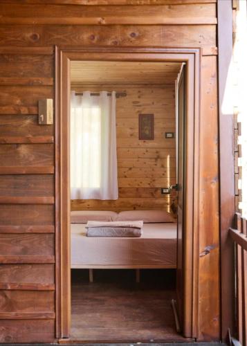 a bed in a wooden room with a window at Captain's House in Mollʼ e Shoshit