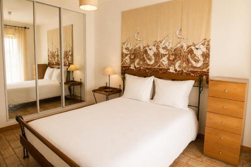 a bedroom with a large white bed and a mirror at Casa da Cuca in Fão