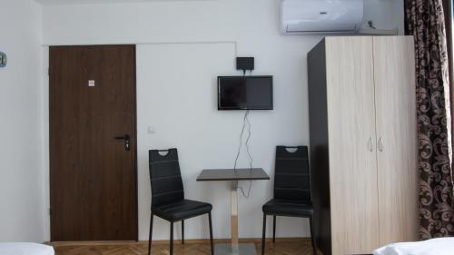 ブルガスにあるThe Old Captain Hostelのテーブル、椅子2脚、テレビが備わる客室です。