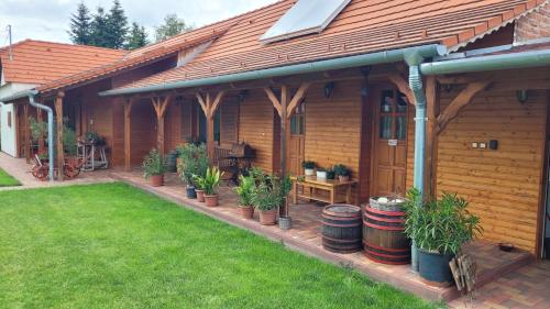 a wooden house with potted plants in a yard at Mura Vendégház in Murakeresztúr
