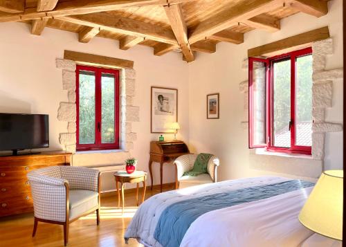 a bedroom with a bed and a tv and windows at Le Manoir du Rocher in Domme