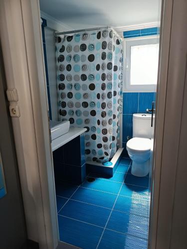 a blue bathroom with a toilet and a shower at Irida's House in Xylokastro