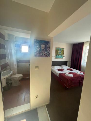 a bedroom with a bed and a bathroom with a toilet at Peshev Family Hotel Nesebar in Nesebar