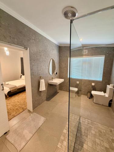a bathroom with a shower and a sink and a bed at Stirling House in Mooiriver