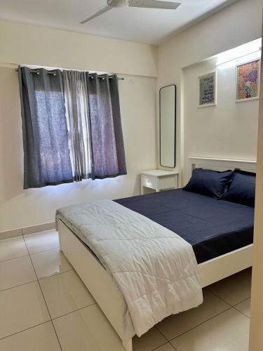 a bedroom with a bed with a blue blanket and a window at North scape 104 in Bangalore