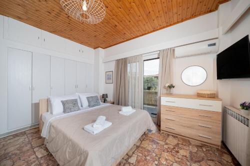 a bedroom with a large bed with a flat screen tv at Porto Marina SeaView in Porto Rafti