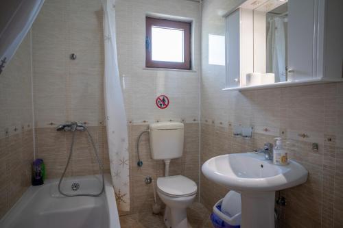 a bathroom with a toilet and a sink and a tub at Apartments Oasis in Budva