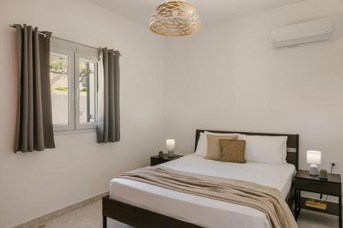 a white bedroom with a bed and a window at Lourdas Sunshine in Lourdata
