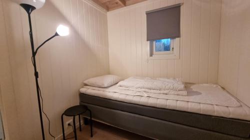 a small room with a bed with a lamp and a window at Brudevoll Gard in Ørsta
