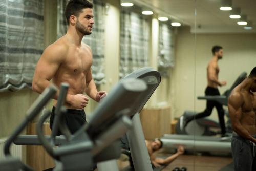 a shirtless man exercising on a treadmill in a gym at Hotel Beskid in Nowy Sącz