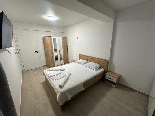 a bedroom with a bed with white sheets and a television at Apartament Meraki Resort&Spa in Năvodari